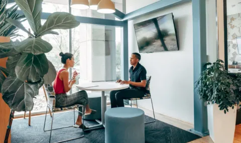 Image of two people sitting at a table in a conference room in a meeting.