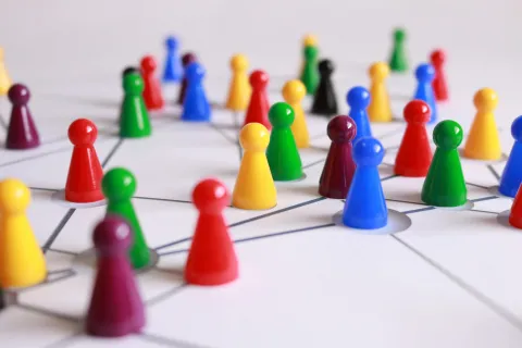 Many colorful chess pieces sit on a table waiting to be moved.