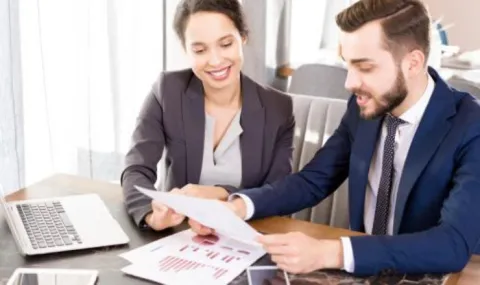 image of a man and a woman in a business meeting reviewing charts and graphs.