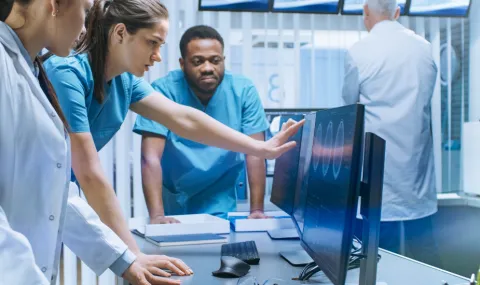 image of a team of health care providers looking at a scan on a computer screen together.