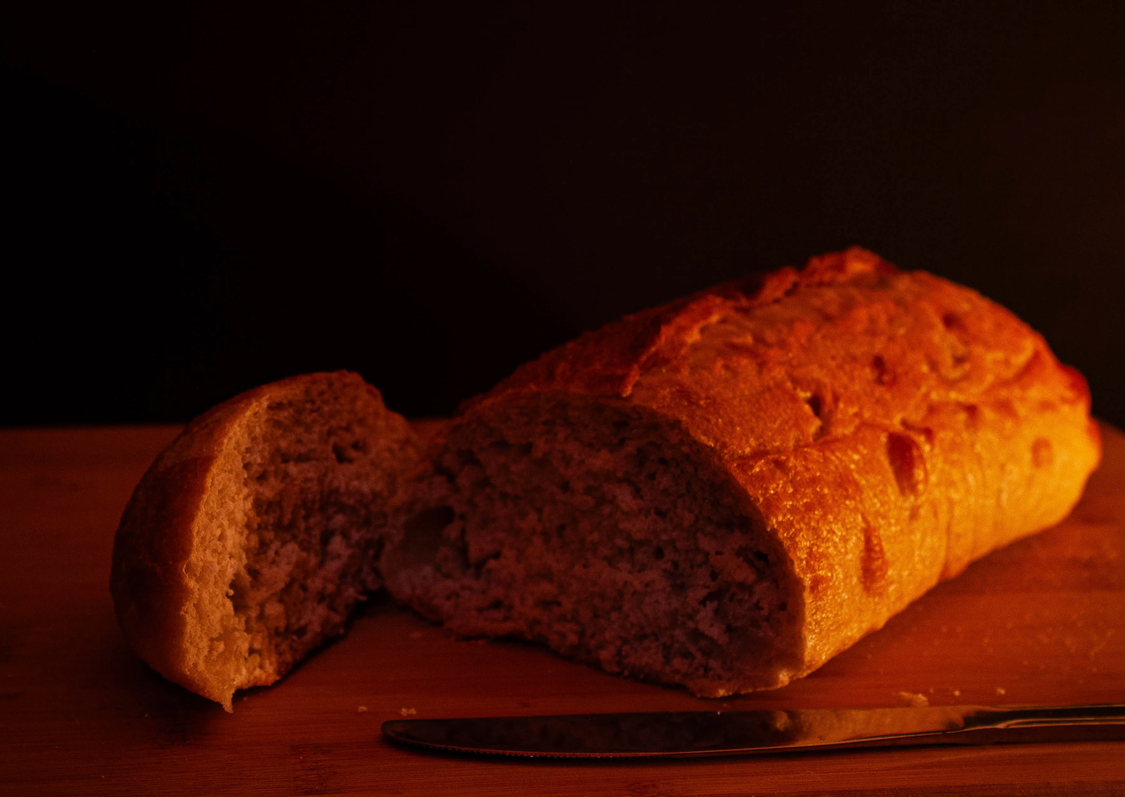 A loaf of sourdough sliced on a cutting board with butter knife